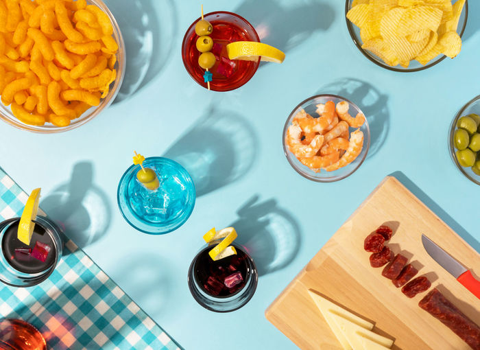 Blue table set with various snacks, appetizers and cocktails
