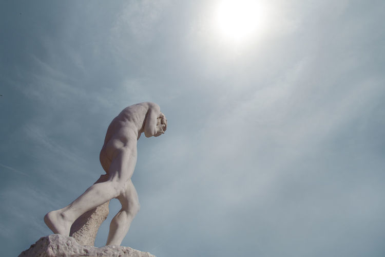 Low angle view of shirtless statue against sky