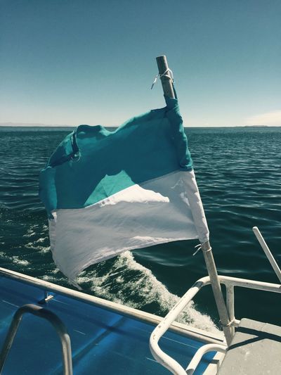 Flag in boat on sea against sky