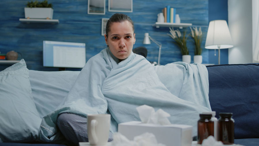 Young woman using mobile phone while sitting on bed
