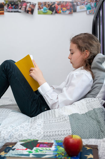 School age girl sitting in her bedroom and doing school homework.