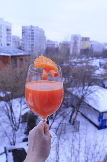 Cropped hand holding carrot juice on the background of winter city
