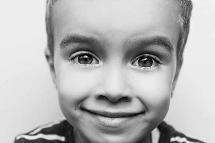Close-up portrait of smiling boy against white background