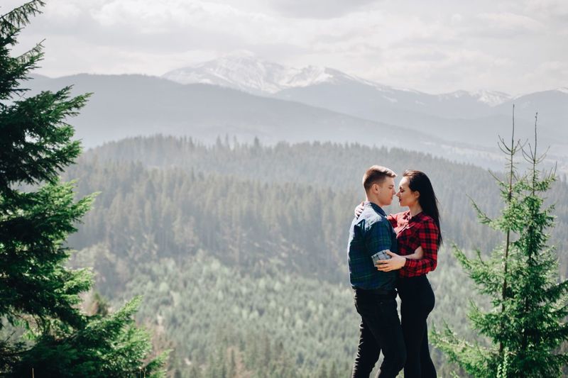 Side view of young couple kissing while standing in forest