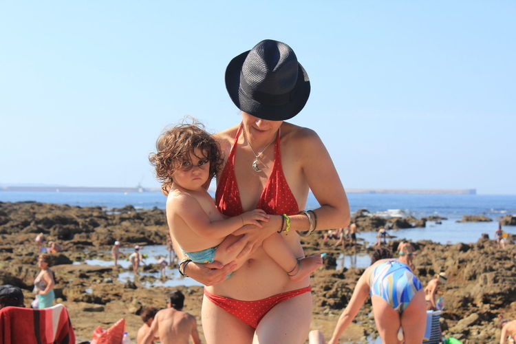 Woman carrying baby girl at beach