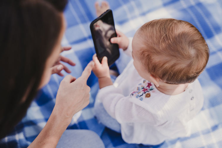 Baby girl with mother holding mobile phone