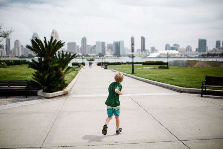 Young boy running with san diego skyline in background