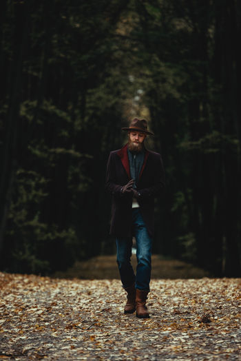 Full length portrait of young man standing against trees