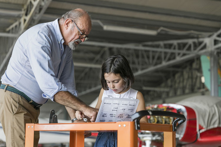 Grandchild and grandfather selecting tools to fix aircraft