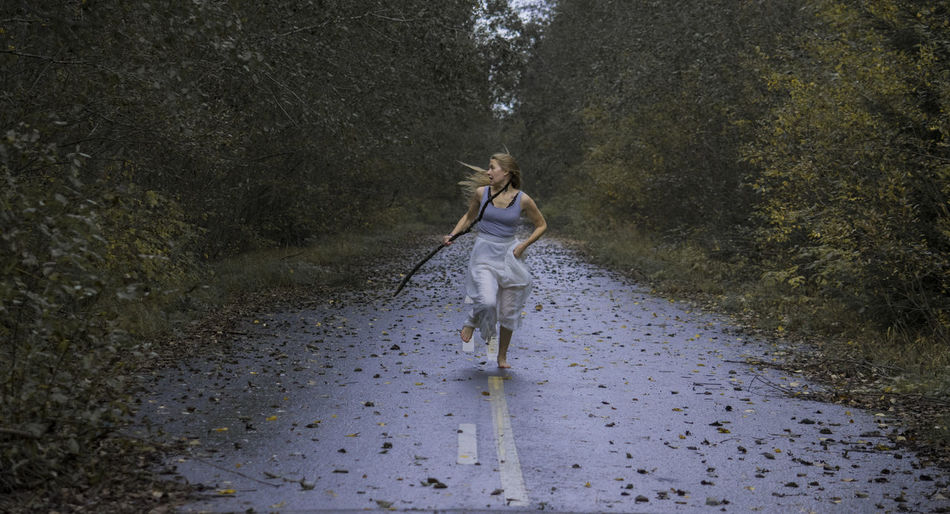 Scared young woman running on footpath in forest