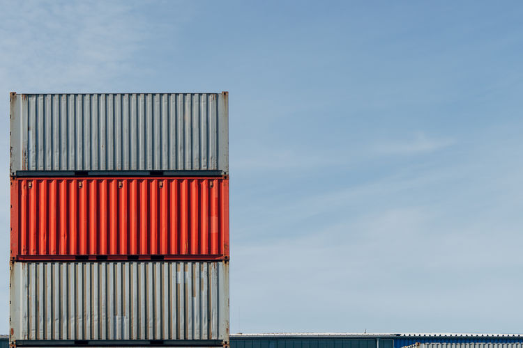 Low angle view of stack of container  against sky
