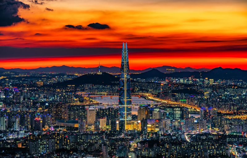 High angle view of illuminated city against sky during sunset