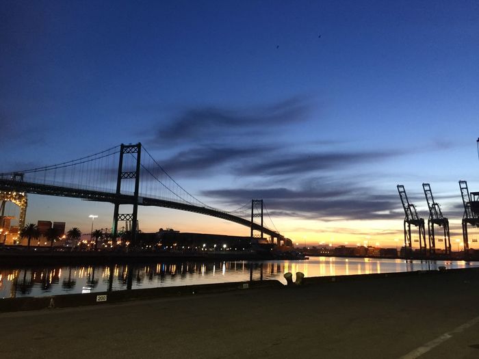 Bridge over river against sky at sunset