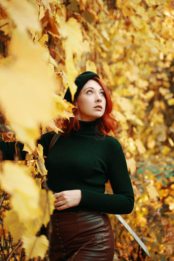 Young woman standing with leaves in autumn
