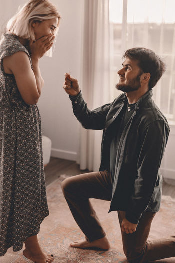 Man kneeling while proposing woman