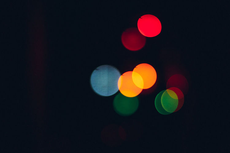 Defocused image of illuminated lights on street at night