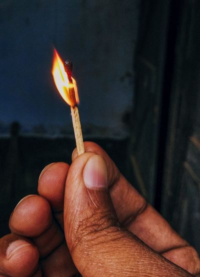 Close-up of hand holding burning candles
