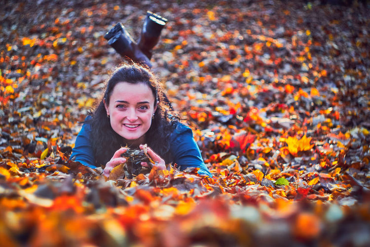 Portrait of smiling woman with leaves during autumn