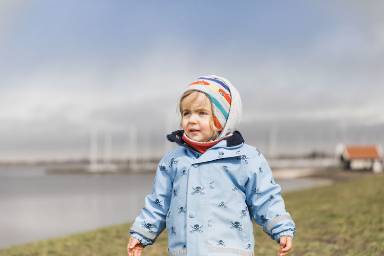Cute girl standing on field against sky