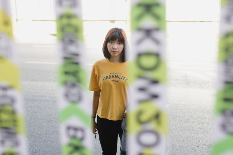 Portrait of young woman standing against blurred background