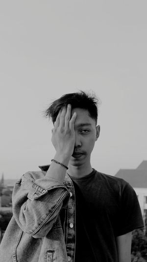 Portrait of young man standing against clear sky