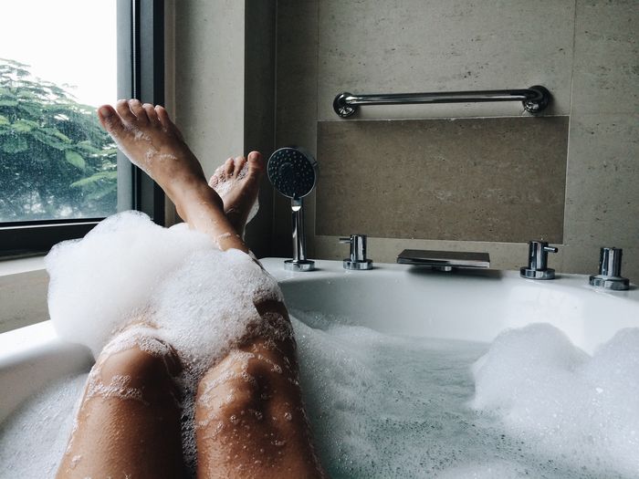 Low section of woman bathing in bathtub