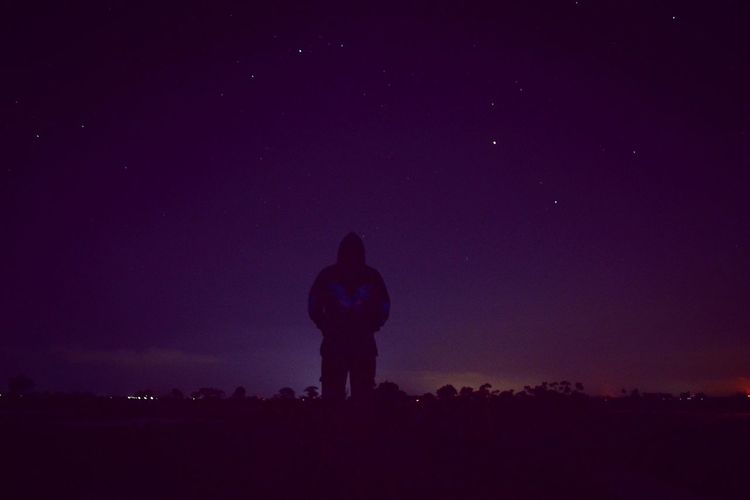 A man standing on field against sky at night