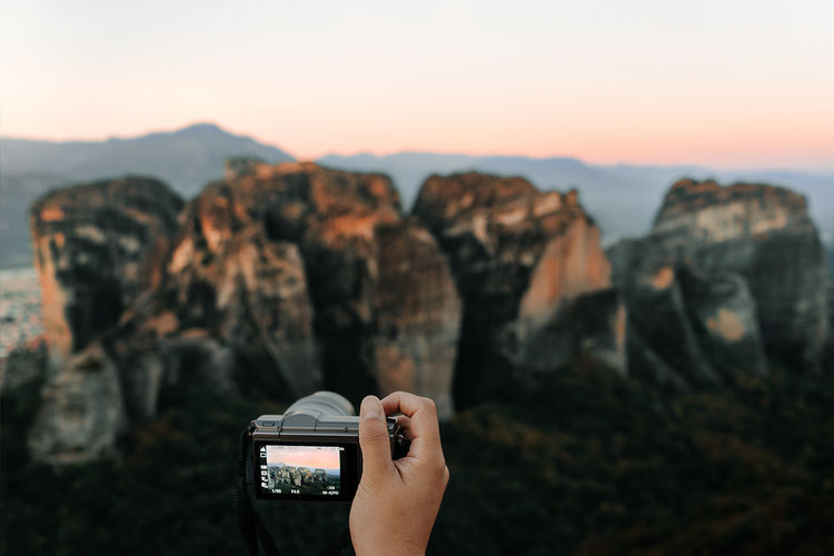 High angle view of person photographing rock formation against sky