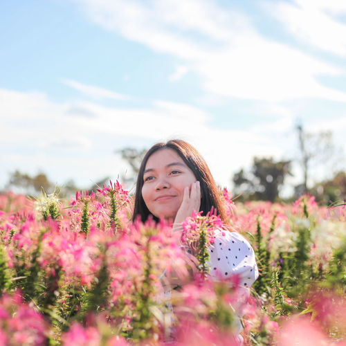 Smiling young woman standing by flowering plants
