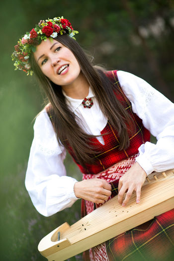 Woman singing and playing koto while sitting against trees