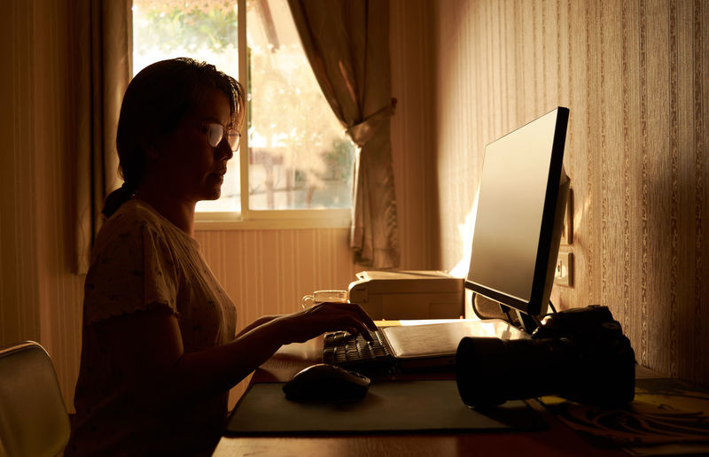 Side view of woman reading book at home