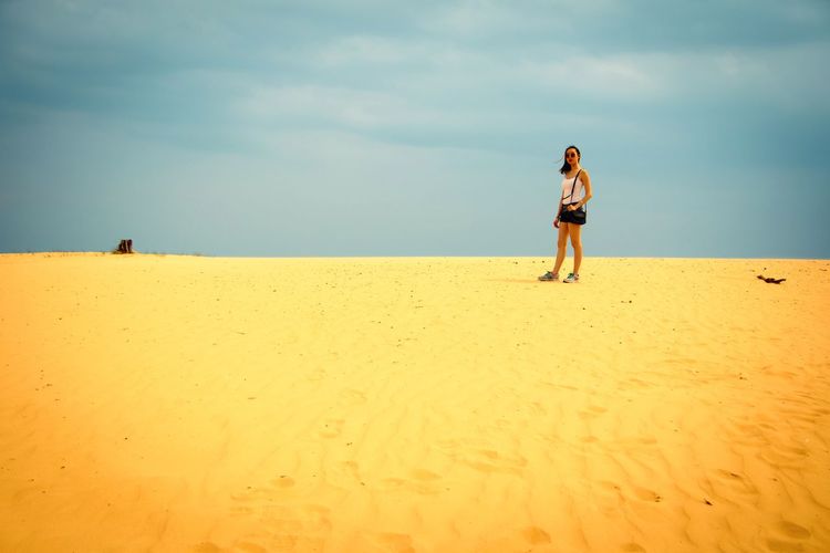 Woman standing on sand at beach against sky