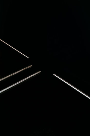 Low angle view of illuminated lighting equipment against black background