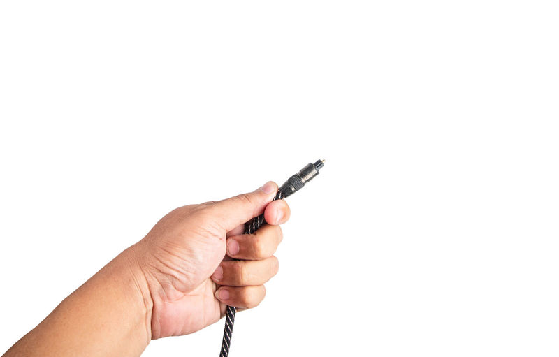 Close-up of hand holding cable against white background