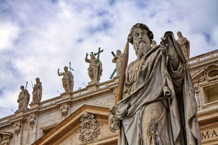 Low angle view of historical building and statue against cloudy sky