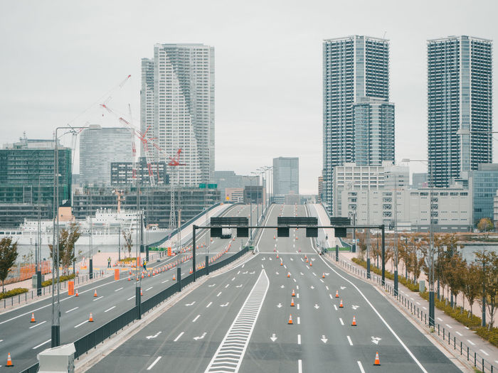 Road by buildings against sky in city