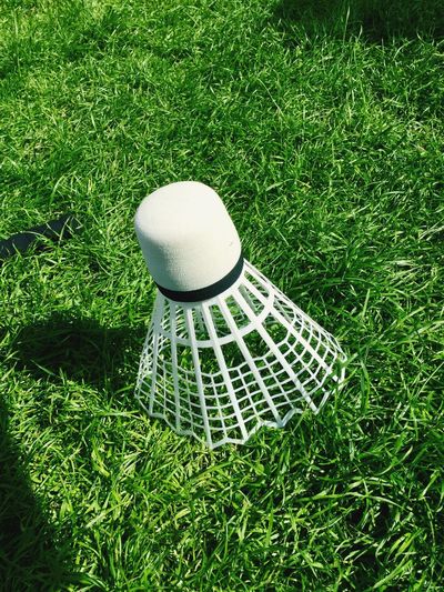 Close-up of shuttlecock on grassy field during sunny day