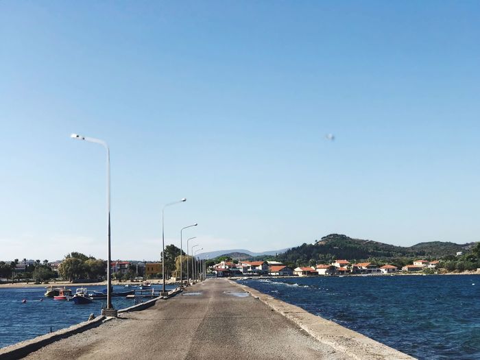 Street by river against clear blue sky