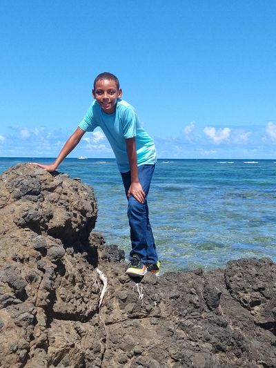 Portrait of boy standing on rock at beach