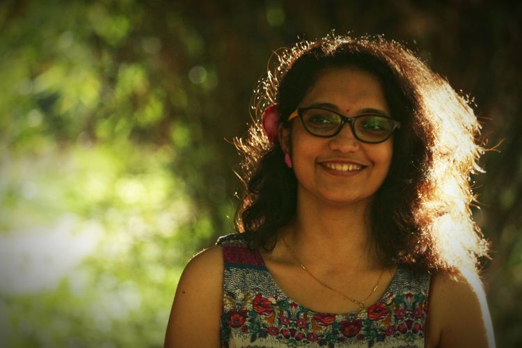 Portrait of smiling young woman wearing eyeglasses standing at park