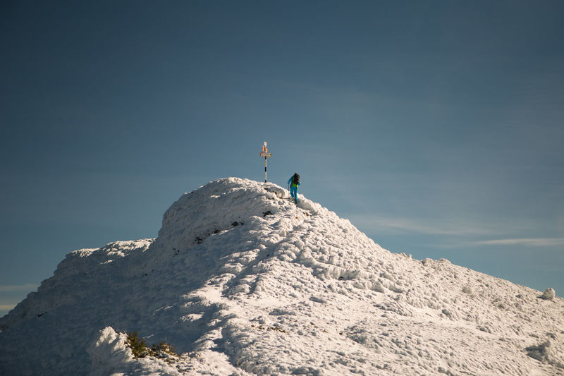 Low angle view of man on snow covered mountain against sky