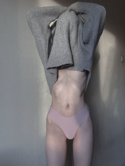 Woman wearing undergarment standing against wall