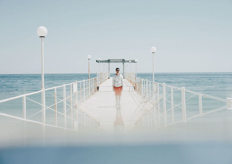 Surface level view of man standing on pier in sea