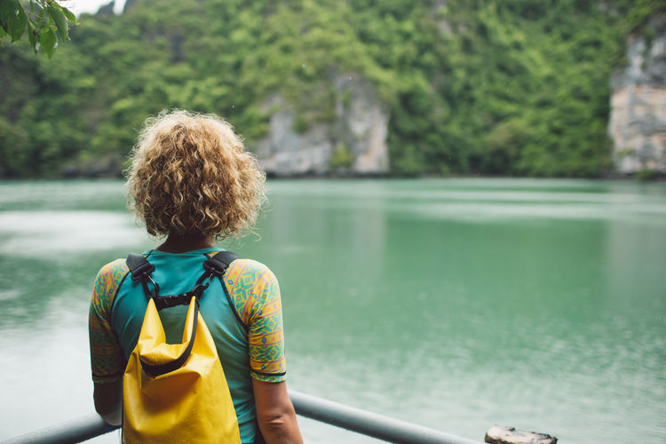 Rear view of woman standing by lake