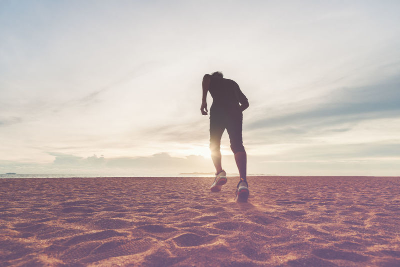 The man with runner on the desert at sunset. running for exercise.