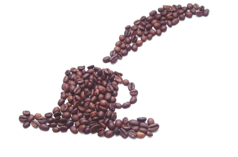 Close-up of coffee beans on table against white background