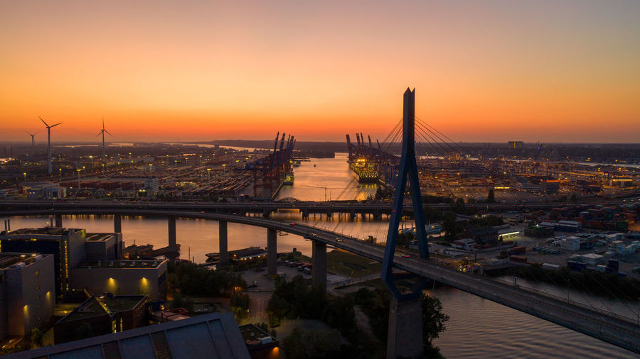High angle view of bridge over river by buildings against sky during sunset