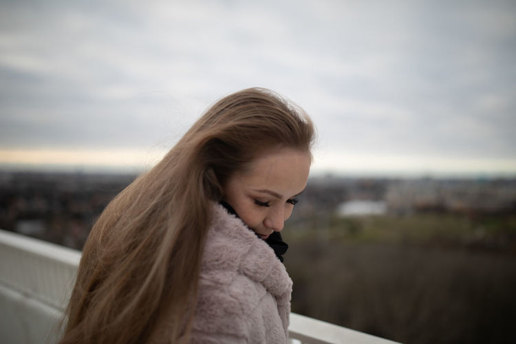 Portrait of beautiful young woman against sky