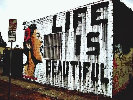 text, architecture, building exterior, western script, graffiti, built structure, communication, wall - building feature, art, creativity, capital letter, art and craft, human representation, sign, low angle view, street art, non-western script, outdoors, day, sky