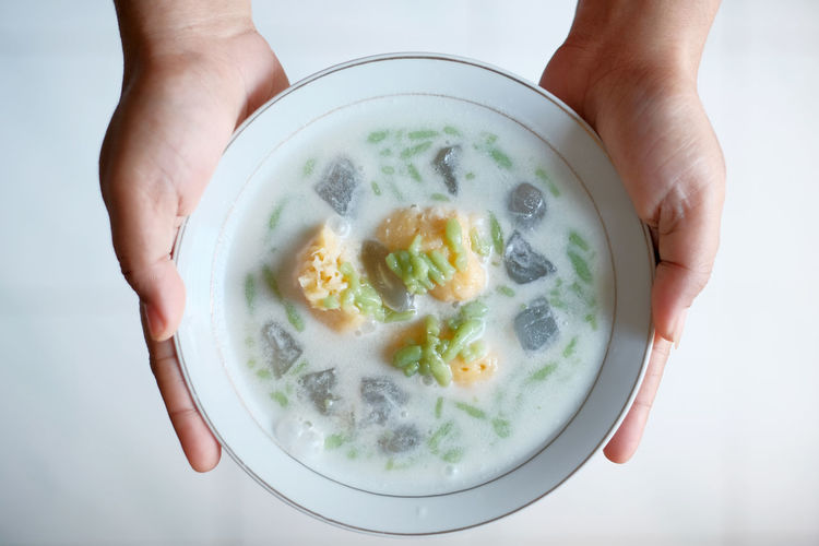 Midsection of person holding bowl of  cendol soup